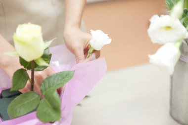 Çiçekçi dükkanda taze gül buketi yapıyor.