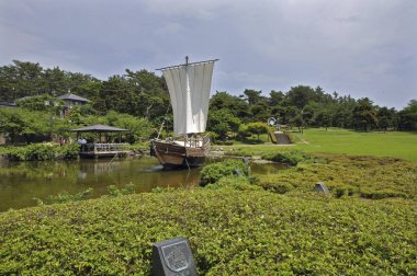 Göl kenarındaki yeşil bahçe, ahşap iskele ve tekne..