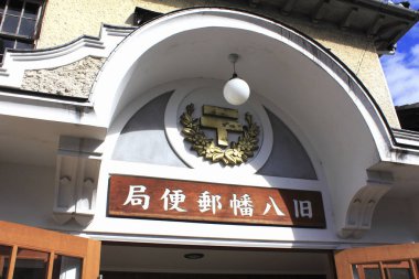 Tarihi bir binanın girişi. Japon işareti ve altın bir posta amblemi var..