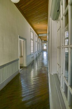Ahşap zeminli ve geniş pencereli uzun koridor.