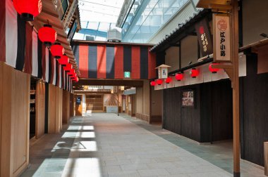 Binaların dışında asılı kırmızı fenerlerin olduğu boş geleneksel Japon caddesi.