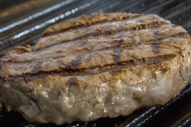 Arka planda kızartma tavasında biftek, yakın çekim.