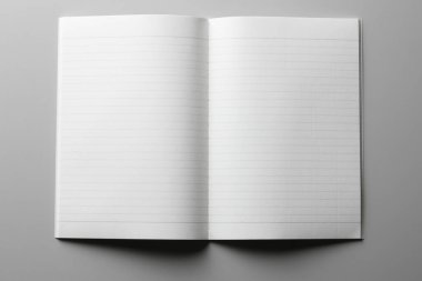 Gri bir yüzeyde beyaz boş bir defter, üst görünüm