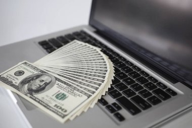 Dizüstü bilgisayarın üstüne para. Arka planda. Kapat.