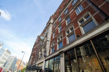 Mavi gökyüzünün altında büyük pencereler bulunan tarihi tuğla bina