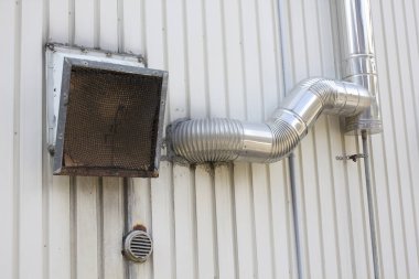 Endüstriyel bina duvarının dışına metal havalandırma kanalı bağlanmış.
