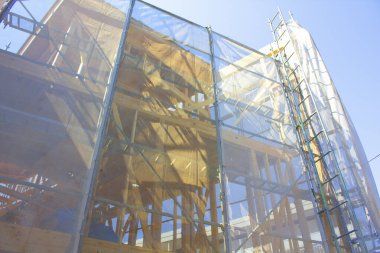 Açık mavi gökyüzünün altındaki bir inşaat alanında iskele..