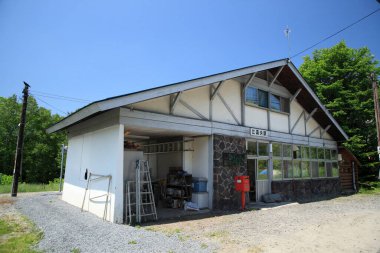Güneşli bir gün, taşralı binanın dış yüzeyini çakıllı garaj yolu ile gösteriyor