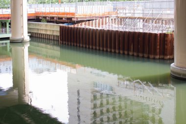 Sakin yeşilimsi su, yakındaki kolonların inşaat alanındaki yapılarını yansıtıyor.