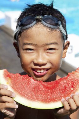 Gülümseyen çocuk dışarıda sulu karpuz dilimleri tutuyor.