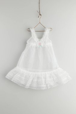 Askıda asılı beyaz bebek elbisesi.