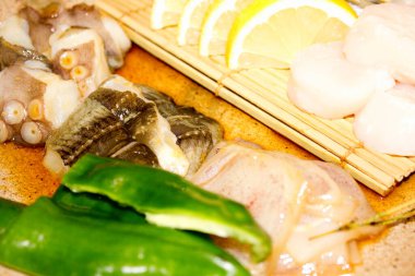 Taze balık filetosu ve limon dilimlerinin yanında yeşil biber.