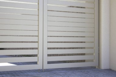 Modern yatay çarpık metal kapı binanın dışına ince gölgeler bırakıyor.