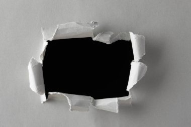 Siyah bir arkaplanda yırtık kağıtta delik    