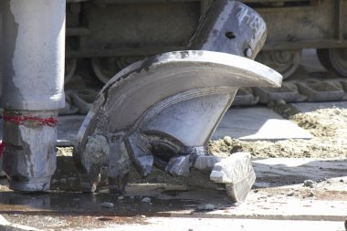 Metal inşaat ekipmanları ıslak beton yüzeyde duruyor.