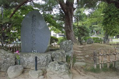 Büyük taş heykel kayalar, ağaçlar ve ahşap çitlerle çevrili.