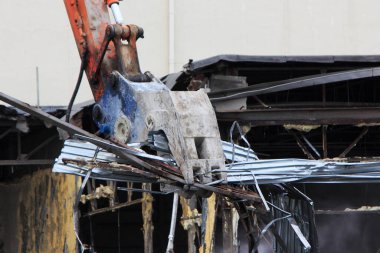 Kazı kazıcı pençesi inşaat alanındaki metal yapıyı yıkıyor