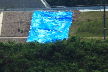 Yol kenarındaki çimleri kaplayan büyük mavi branda.