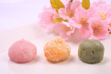 Japon tatlılarının ve açık arkaplanda pembe çiçeklerin yakın plan görüntüsü.        