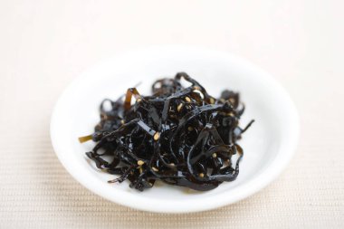 Koyu deniz yosunlarıyla dolu küçük beyaz tabak.