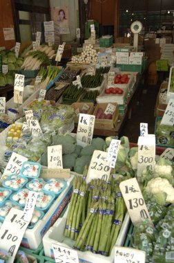 Açık hava pazarında etiketli taze sebzeler sergileniyor.