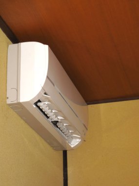 Tarafsız renklere ve minimal tasarıma sahip modern bir odanın tavanına monte edilmiş verimli bir havalandırma ünitesi.