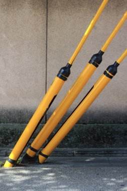 Beton duvara yaslanmış üç sarı direk.