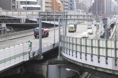 Bulutlu bir günde modern şehir sokaklarında trafik akıyor.