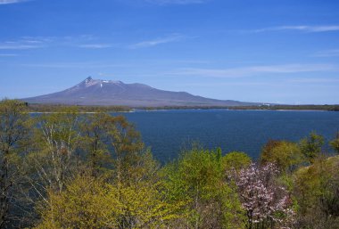 Mavi gökyüzü ve arka planda dağlar olan güzel göl manzarası.           