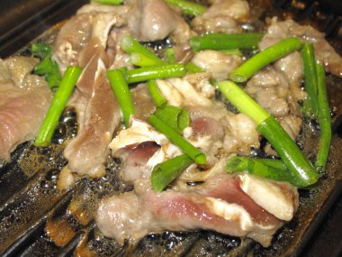 Tavada yeşil soğanlı kızarmış domuz kızartması.