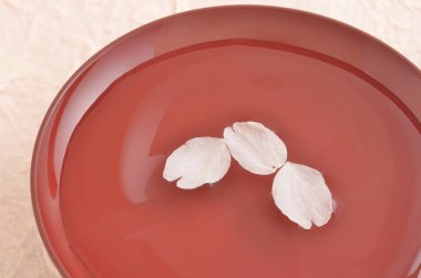 Açık bir yüzeyde, bir kasede pembe gül yapraklarının yakın çekimi.