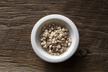 Tahta arka planda bir kasede beyaz soya fasulyesi..