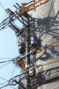 Gökyüzü arka planında yüksek voltaj elektrik direği ve elektrik kabloları.