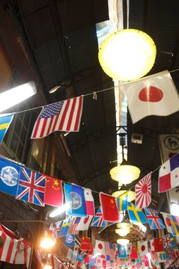 Kalabalık pazar salonunda renkli uluslararası bayraklar sallanıyor