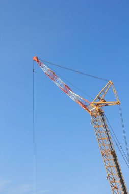 Mavi gökyüzü arka planında inşaat vincinin düşük açılı görüntüsü              