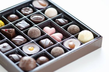 Beyaz arka planda kutuda çeşitli lezzetli çikolataların yakın plan görüntüsü    