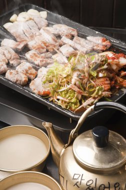 Kızarmış domuz eti, sebze ve su ısıtıcısı.