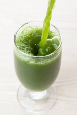 Açık arkaplana dökülen yeşil, taze, sağlıklı organik içeceğin yakın plan görüntüsü.                                          