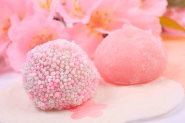 Japon tatlılarının ve açık arkaplanda pembe çiçeklerin yakın plan görüntüsü.        