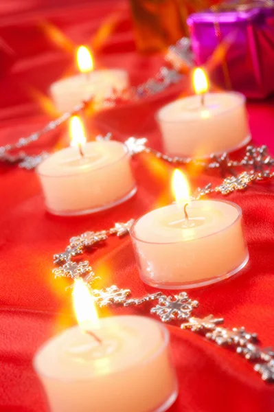 在桌上的红色圣诞装饰品上点着蜡烛 — 图库照片