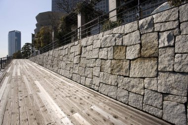 Açı açılı manzara, tahta tahta kaldırımın yanında taş duvar olduğunu gösteriyor.