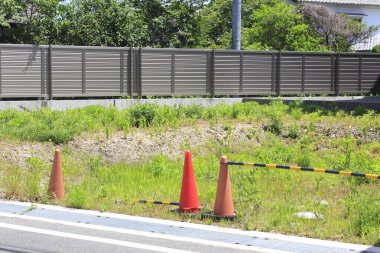 Yol kenarındaki çimenli inşaat alanını gösteren turuncu trafik konileri