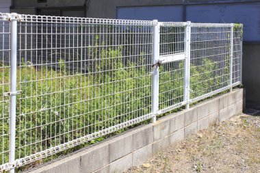 Beyaz metal çit ve yeşil bitkiler