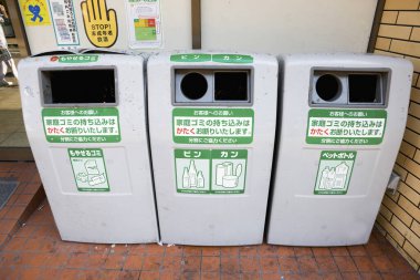 Üç etiketli geri dönüşüm kutusu. Kapalı kapılar ardında duruyor.