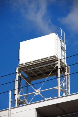 Endüstriyel soğutma ünitesi arka planda açık mavi gökyüzü olan bir çatıda.