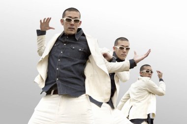 Beyaz stüdyoda dans eden üç Asyalı genç adam.