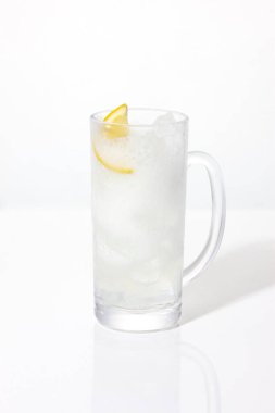 Beyaz arka planda izole edilmiş cam bardakta taze limon dilimi.