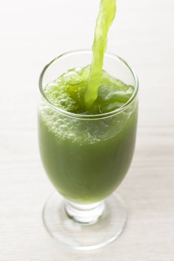 Açık arkaplana dökülen yeşil, taze, sağlıklı organik içeceğin yakın plan görüntüsü.                                          