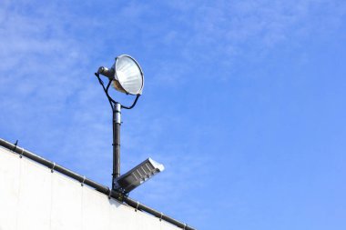 Açık hava güvenlik kamerası ve projektör ışıkları bina duvarının üzerine monte edildi
