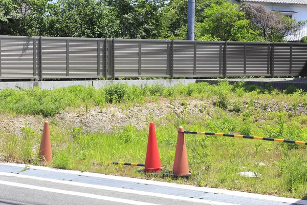 Yol kenarındaki çimenli inşaat alanını gösteren turuncu trafik konileri